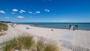 a beach with people on the sand and the water at Ferienhof Kluvetasch Appartement Nr 4 Ostseeblick in Rettin