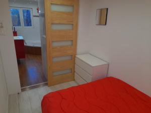 a bedroom with a red bed and a bathroom at La campagne dans l'Ocean à LA ROCHELLE les pieds dans la grange in Croix-Chapeau