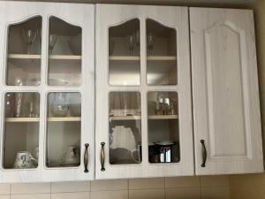 un armario blanco con puertas de cristal en la cocina en Green Hills II by Rent a car MI en Podgorica