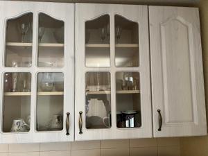 a white cabinet with glass doors in a kitchen at Green Hills II by Rent a car MI in Podgorica
