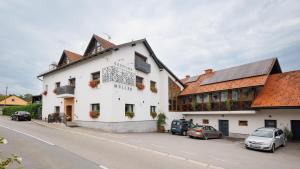 a white building with cars parked on a street at Gostilna Müller in Črnomelj