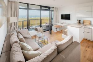 a large living room with a large couch and a kitchen at SeaScape in Norderney