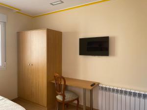 1 dormitorio con escritorio y TV en la pared en PENSIÓN SANTA CLARA, en Pontevedra