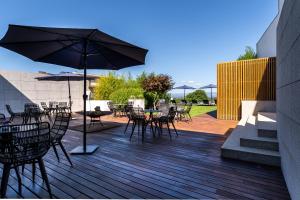 a deck with tables and chairs and an umbrella at 4615 Hotel in Felgueiras