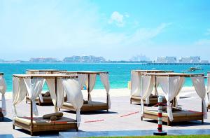 un grupo de sillas y mesas en la playa en Icon Casa Living - Rimal 3 Residence - JBR, en Dubái