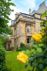 ein altes Haus mit gelben Blumen davor in der Unterkunft Grosvenor Villa in Bath