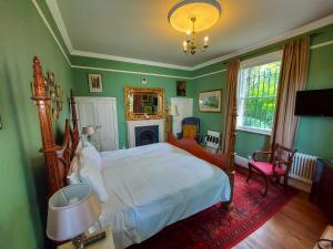 um quarto com uma cama com paredes verdes e uma lareira em Grosvenor Villa em Bath