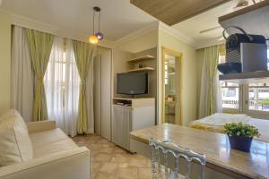 a kitchen and living room with a table and a television at Villas Jurerê Hotel Boutique in Florianópolis