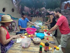 un grupo de personas de pie alrededor de una mesa preparando comida en Kibbutz Lotan Eco-Campus 