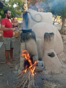 un hombre parado frente a un horno con fuego en Kibbutz Lotan Eco-Campus, 