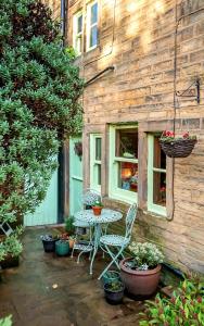 a patio with a table and chairs and potted plants at Cottage Pie - 10mins easy walk to Holmfirth in Holmfirth