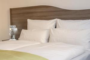 Cama blanca con cabecero de madera y almohadas blancas en Rhöner Ferienwohnung, en Stadtlengsfeld