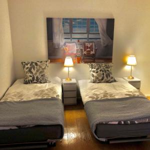 two beds in a room with two lamps and a window at Gemuetliche 2 Zimmer Wohnung mit Gartensitzplatz in Fällanden