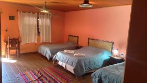 2 letti in una camera con pareti arancioni di hosteria camino del inca a Humahuaca