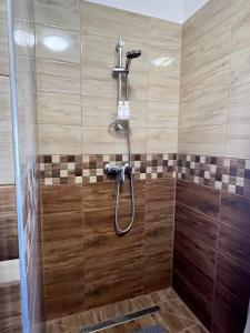 y baño con ducha y azulejos de madera. en Edmond Apartment, en Hévíz