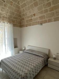 a bedroom with a bed and a stone wall at Donna Maria Pina in Monopoli