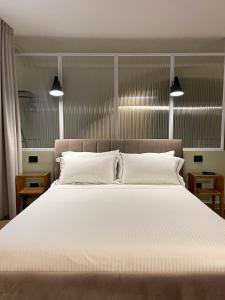 um quarto com uma grande cama branca e 2 luzes em Raha Suites em Siracusa