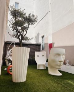 two white sculptures sitting on the grass in front of a building at Casa Del Profumo in Piacenza