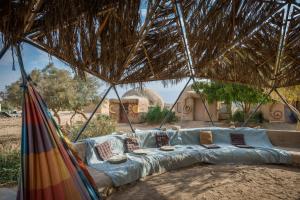 a couch under a straw umbrella in front of a building at Kibbutz Lotan Eco-Campus 