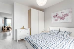 biała sypialnia z łóżkiem, komodą i lustrem w obiekcie Chill Apartments Ursus w Warszawie