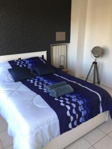 a bed with a blue and white comforter and pillows at SETE - 6 Quai Louis Pasteur in Sète