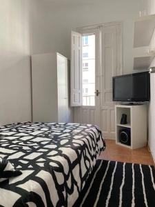 a bedroom with a bed and a flat screen tv at Parque El Retiro Madrid in Madrid