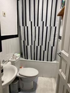biała łazienka z czarno-białą zasłoną prysznicową w obiekcie Parque El Retiro Madrid w Madrycie