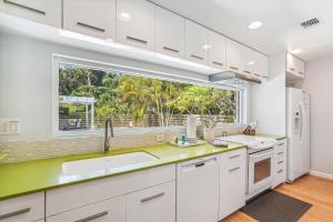 a kitchen with white cabinets and a large window at Sapphire Shores - Sarasota Bungalow w/ Heated Pool and Backyard Oasis in Sarasota