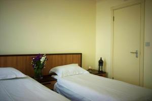 two beds in a room with a vase of flowers at Pembury Hotel at Finsbury Park in London
