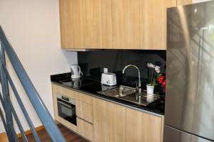 a kitchen with a sink and a stainless steel refrigerator at Casa João Eusébio 2 in Ponte de Lima +2 photos