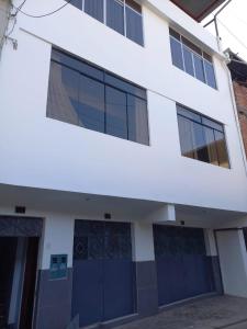 a white building with blue doors and windows at Hospedaje Margarita in La Merced