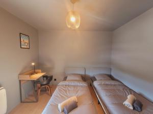 - 2 lits dans une chambre avec une table et un bureau dans l'établissement Bel appartement contemporain proche des commodités, à Toulouse