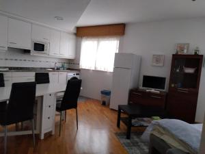 a kitchen with white cabinets and a table and chairs at Piso con piscina en Sada in Sada