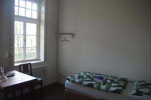 a bedroom with a bed and a table and a window at Zöllnerhaus Nordhorn in Nordhorn