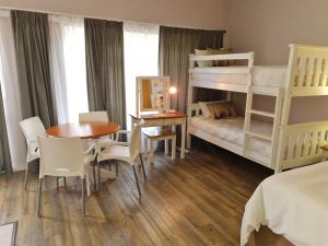 10 Windell Self Catering Accommodation في دوربانفيل: غرفة نوم بسريرين بطابقين وطاولة وكراسي