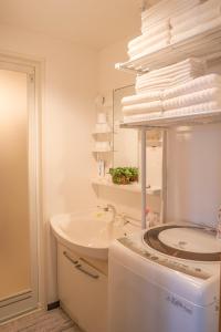 bagno bianco con lavandino e lavatrice di 久Hisashi新栄店民泊 a Nagoya