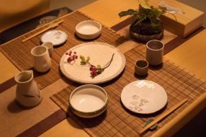 a table with white plates and cups on a wooden table at 久Hisashi新栄店民泊 in Nagoya