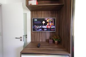 een kamer met een televisie aan de muur en een bureau bij Manhattan Riviera Beach in Aquiraz