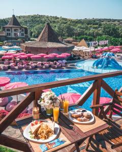 a table with plates of food next to a swimming pool at The Wind Mills Hydropark in Gorna Malina