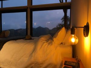 uma cama num quarto com uma grande janela em Futucatuia Brisa Chalé nas montanhas em Gonçalves