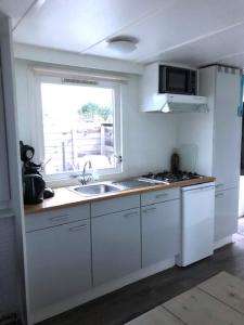 a white kitchen with a sink and a window at Sinne in Ballum