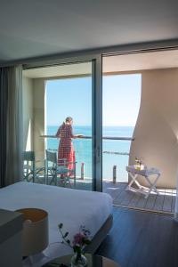 een vrouw op het balkon van een hotelkamer bij Hotel Excelsior in Pesaro