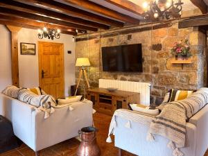a living room with two white chairs and a tv at Casa Rural Puerto del Escudo in Cilleruelo de Bezana