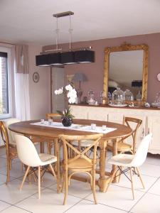 einen Esstisch mit Stühlen und einem Spiegel in der Unterkunft Gîte du Grand Cerf in Criquiers