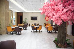 un restaurante con mesas y sillas y un árbol con flores rosas en Hôtel FAMILLE MONDIALE en Abiyán