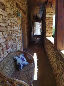 a hallway with a wicker bench in a stone wall at La ferme du vincent in Liergues