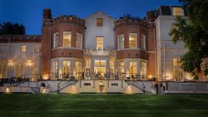 メイデンヘッドにあるTaplow House Hotel & Spaの夜の大邸宅前に立つ男