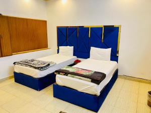 two beds in a room with blue and white at Hotel Mehran Multan in Multan