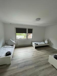 Cette chambre blanche dispose de deux lits et d'une fenêtre. dans l'établissement estrella24 LIVING ROOMS London, à Herne