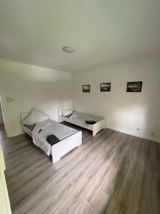 - 2 lits dans une chambre dotée de parquet dans l'établissement estrella24 LIVING ROOMS London, à Herne